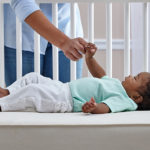 Baby lying on the hus back on the Sealy Natural Rest Crib Mattress
