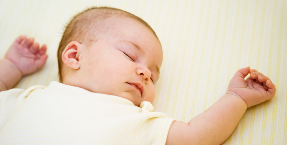 image of baby sleeping on back with hands up.